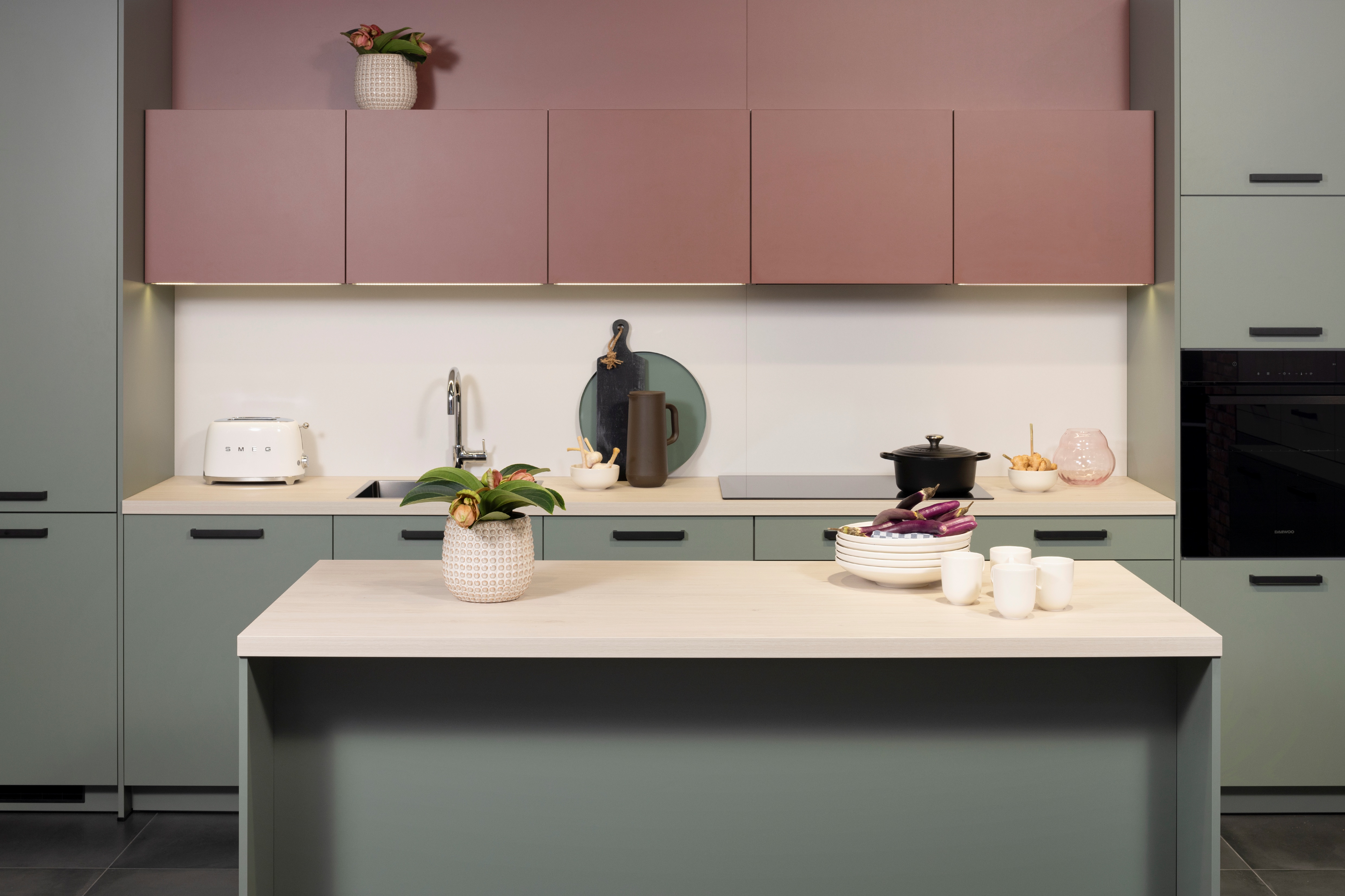APL: White Oak Front: Pastell Eukalyptus Front: Pastell Oxidrot Korpus: Seidengrau Griff: Bügelgriff Geräte: Daewoo Armatur: Ukinox Spüle: Ukinox  Features: neue Fronten in Pastell kombiniert, neuer Haubenschrank für Dunstabzug, Handtuchhalter-Auszug, eingekofferte Wandschränke mit Klappe.