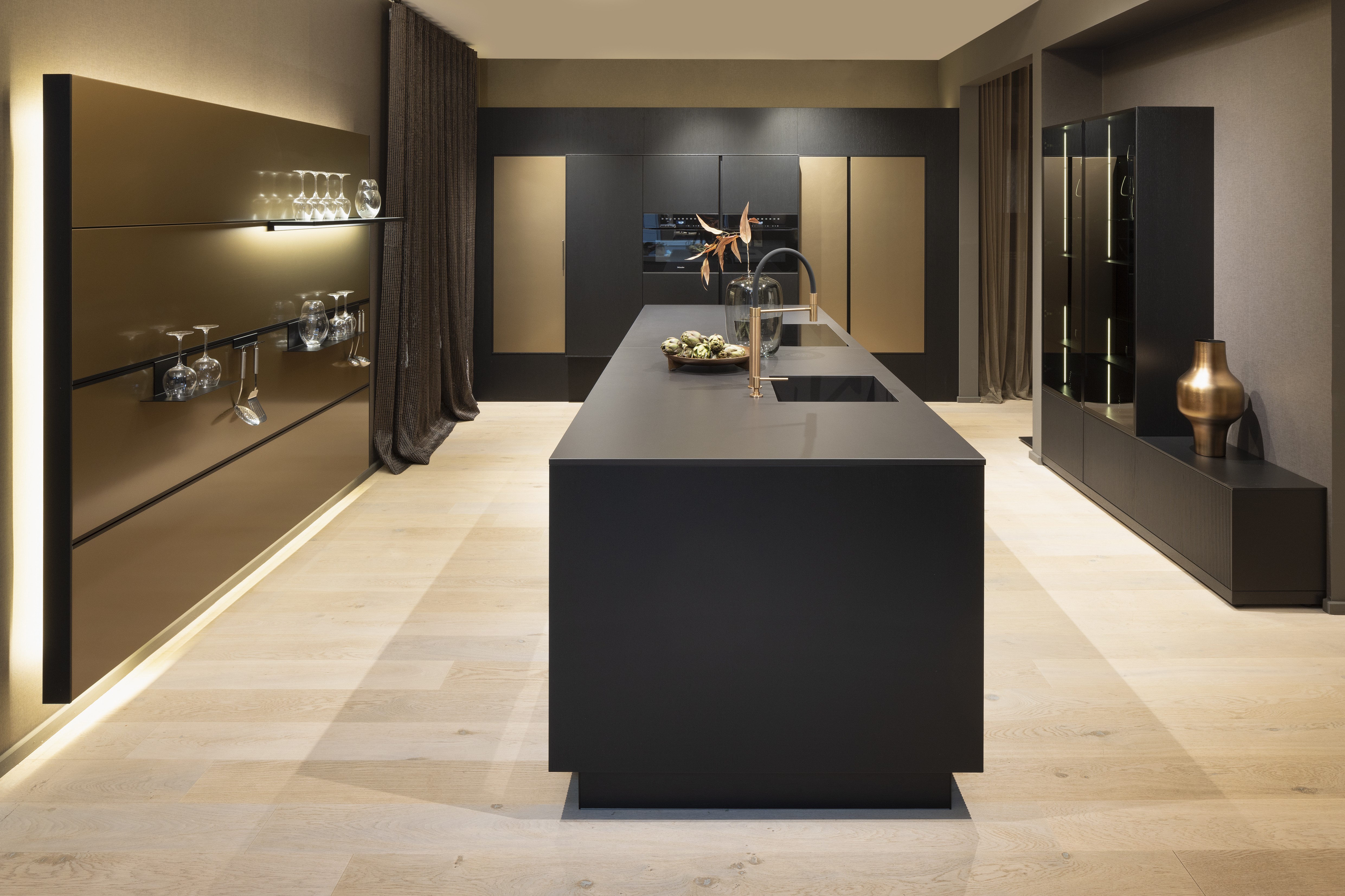 APL: Silk Negro Naturale (Keramik) 16 mm   Front: AV 6023-GL Eiche-schwarz Echtholzfurnier Rille AV 7070 Industriestahl Bronze, Metalliclack Korpus: 4059 Titan Griff: Kehlleiste 355 Schwarz matt Geräte: Miele Armatur: Gessi Features: Regalwandlösung mit beleuchtetem Wandboard, Oberfläche von Hand bearbeitet, Materialmix, Trendthema Bronze, Glasschublade mit Plexiglas in Schwarz getönt, Thekenlösung mittig, Wand aus Oberflächenmaterial in Bronze mit beleuchteten Funktionsleisten für Gläser, etc. 