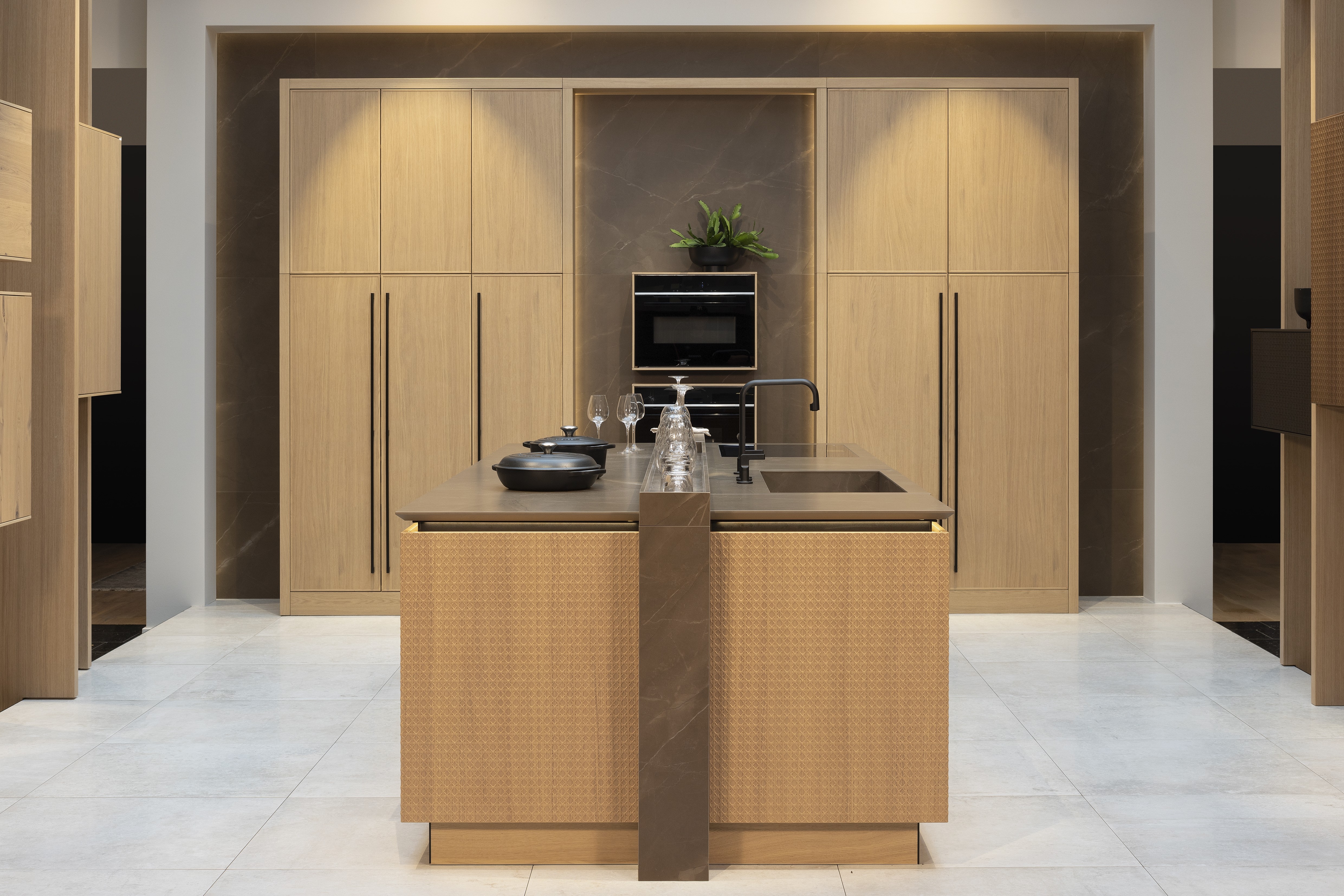 APL: Pulpis (Keramik) 25 mm Front: AV 6085-GL Eiche-elegant Echtholzfurnier (PURemission) Korpus: 2085 Designkorpus Feineiche-natur Griff: Kehlleiste 355 Schwarz matt Geräte: Siemens  Armatur: Gessi Spüle: ?  Features: neue Oberfläche Wiener Geflecht in Echtholzfurnier, Oberflächenmix, Waschbecken (Spülstein) in APL-Material, schwebende Arbeitsplatte durch Lichtleiste, APL abgekantet (schwebend), Backöfen in Wand eingekoffert, 3 Materialfarben.