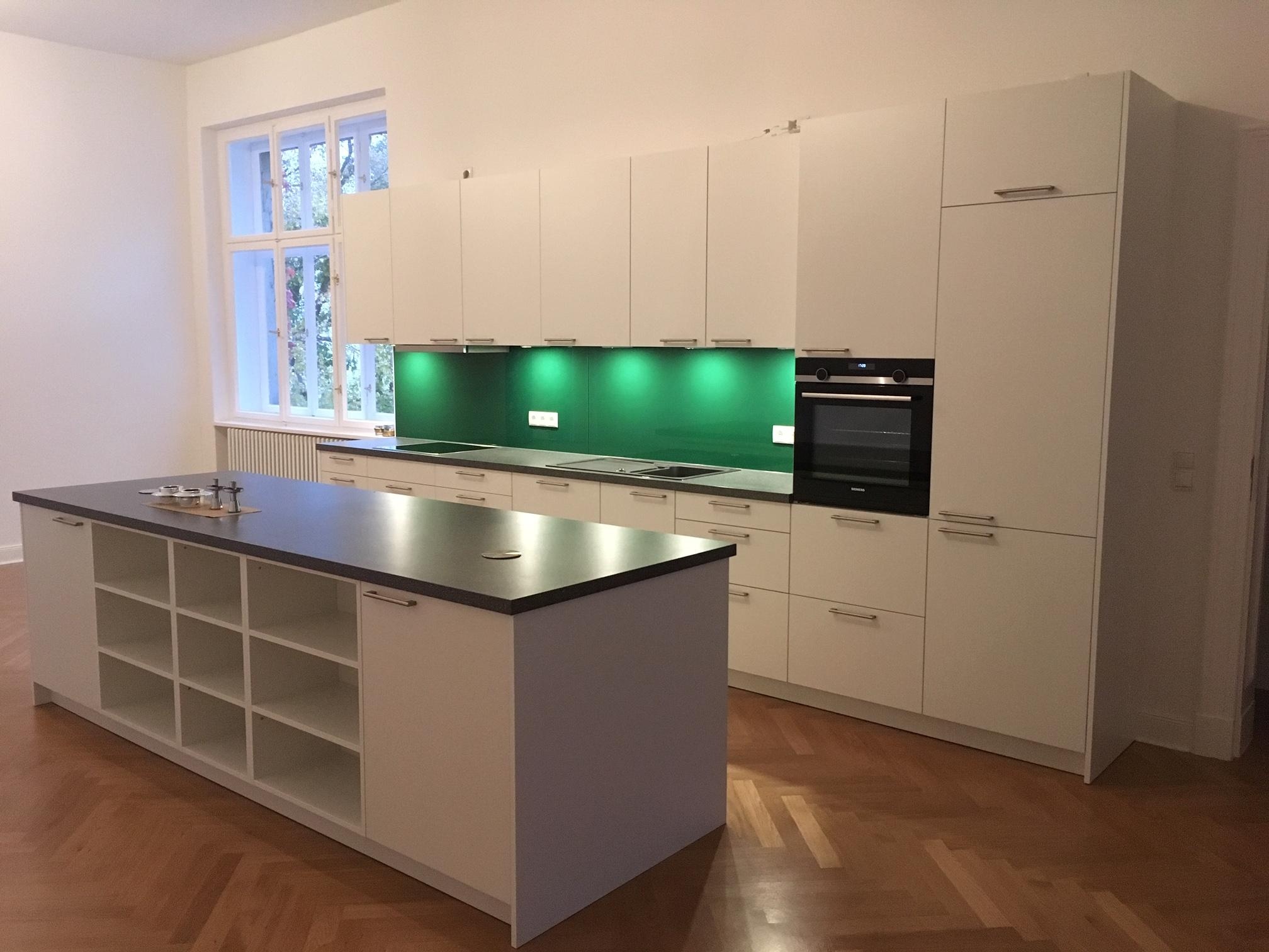 Küchenzeile weiß mit Nischenrückwand grün glänzend plus Kücheninsel mit offenen Regalfächern und Arbeitsplatte dunkel