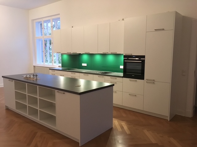 Küche mit Insel und Nischenrückwand Glas Grün
