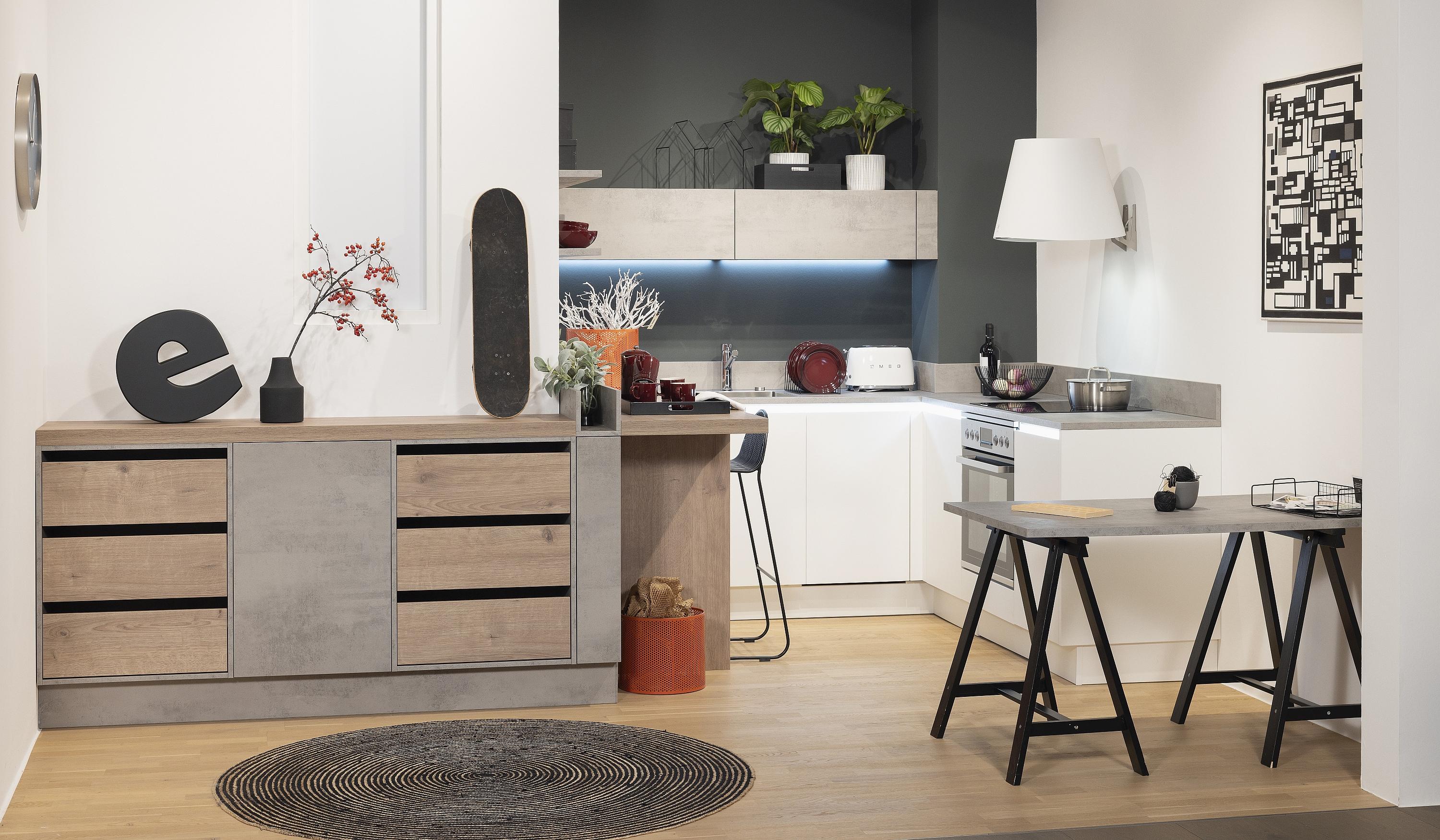 Im Vordergrund Sideboard mit englischen Zügen im Hintergrund in einer Nische kleine weiße Küche mit Esstheke in Holz unter hoher Dachschräge